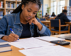 Student working through a past exam paper at a library desk.